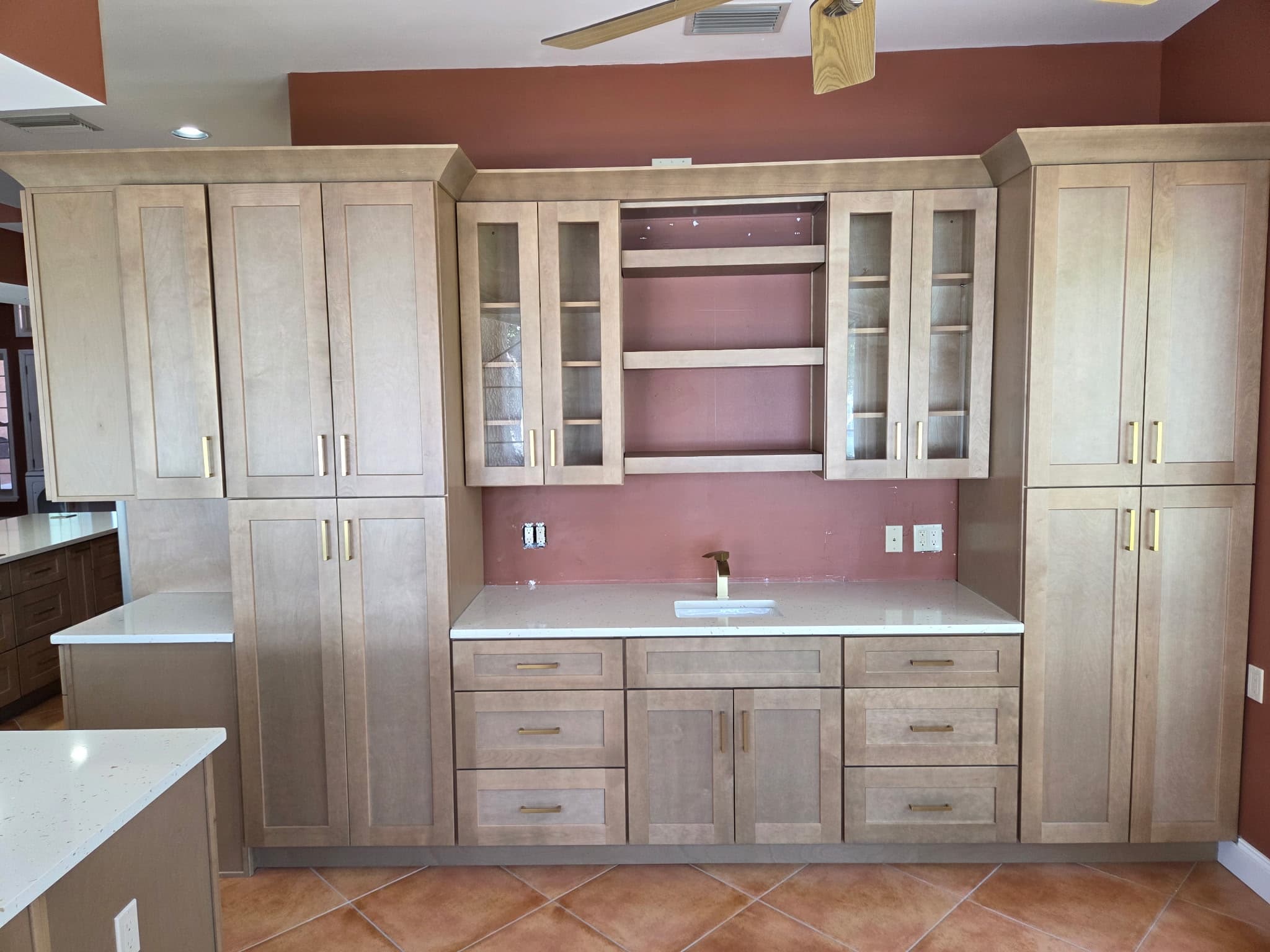 KJB Construction waterfront kitchen cabinetry wall with natural birch shaker cabinets, glass-front doors, open shelving, brass hardware, and quartz countertop
