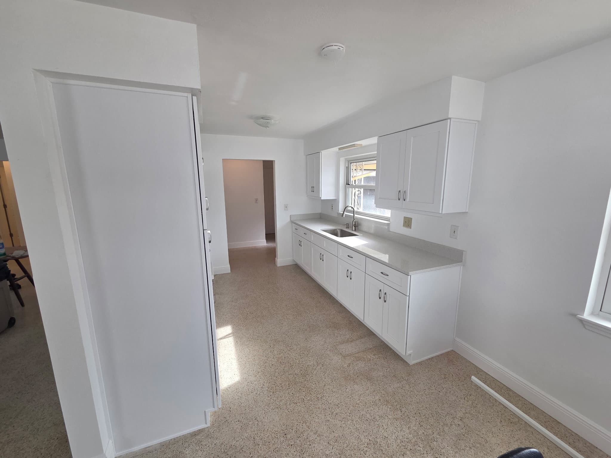 KJB Construction galley kitchen renovation with white shaker cabinets, grey quartz countertop, and terrazzo flooring