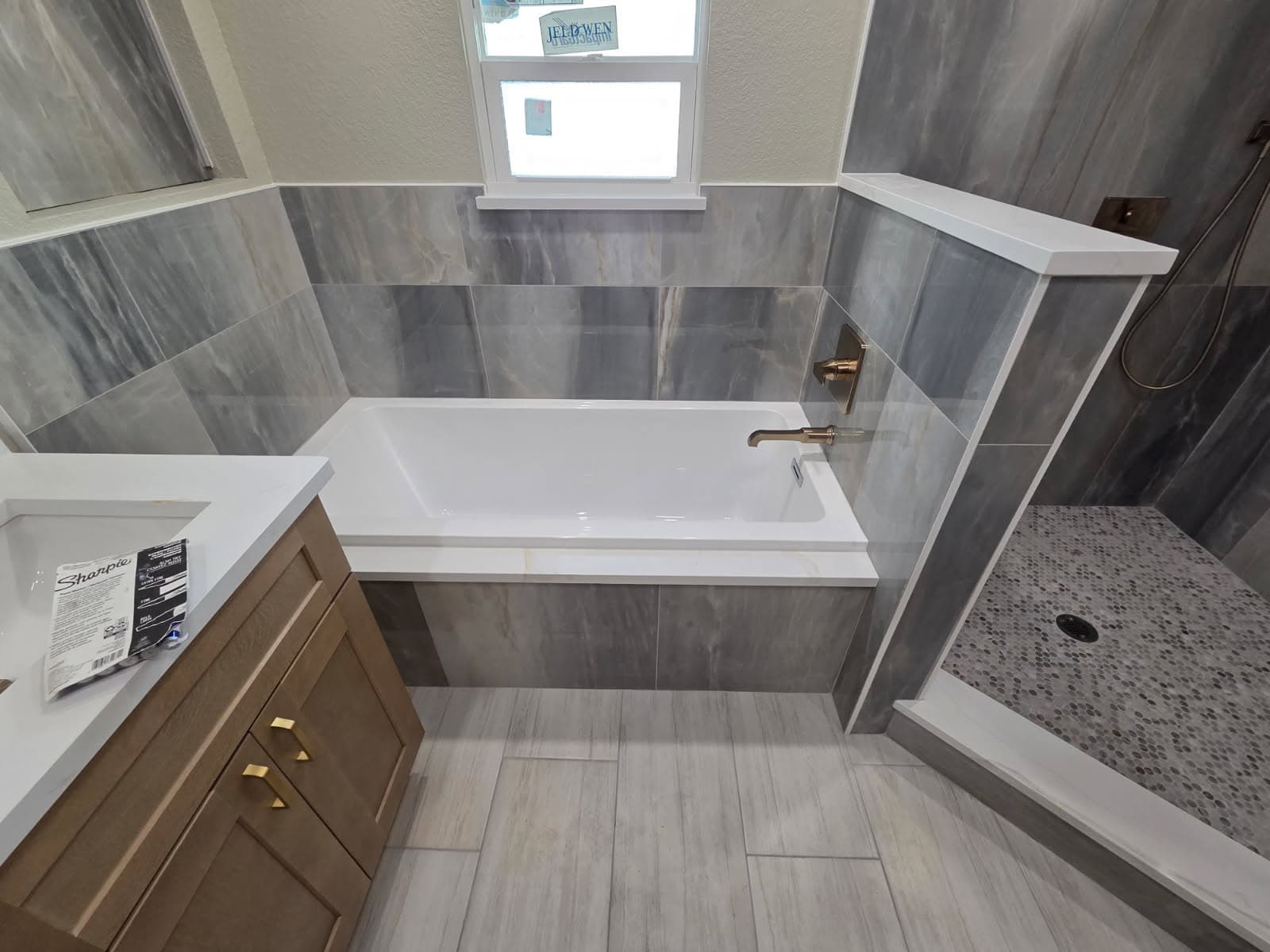 KJB Construction master bath wide angle with soaking tub, wood vanity with brass hardware, and walk-in shower