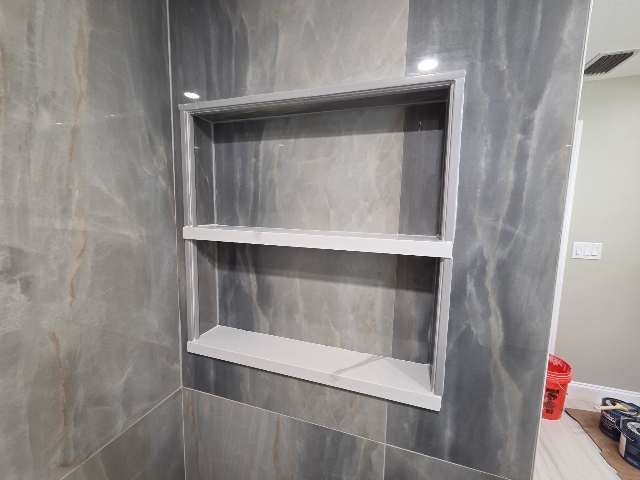 KJB Construction custom dual-shelf shower niche with grey marble tile surround
