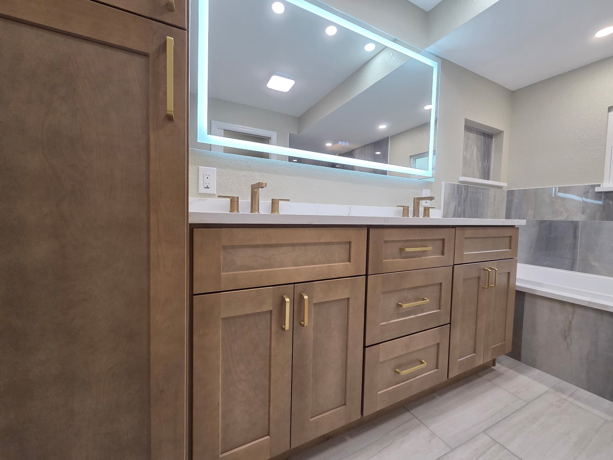 KJB Construction custom double vanity with brass hardware, quartz countertop, and LED backlit mirror