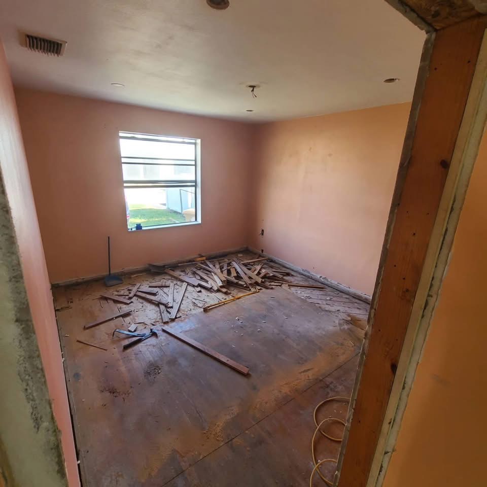 Bedroom before renovation - construction phase with exposed subfloor and debris
