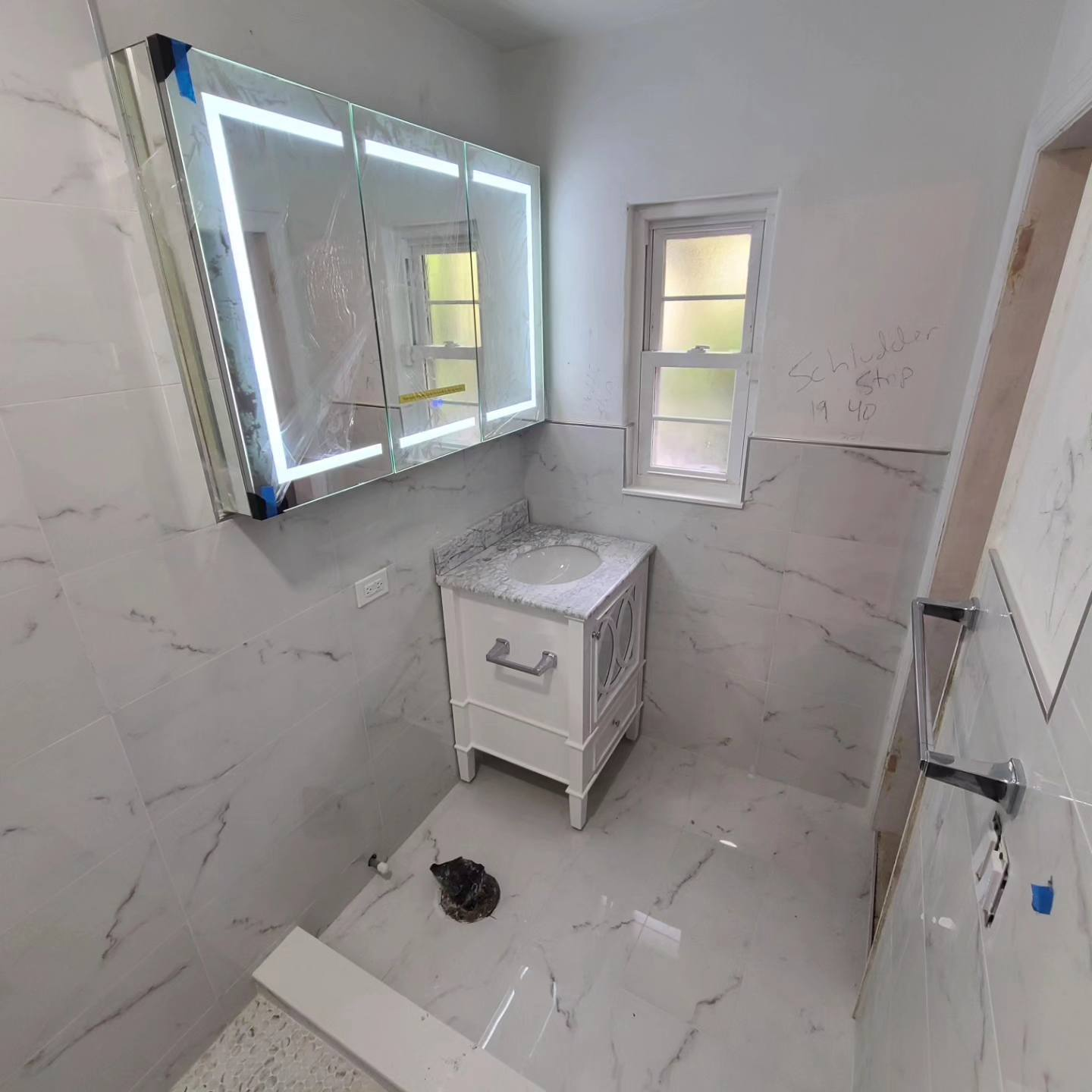 Bathroom under construction with white marble tile installation