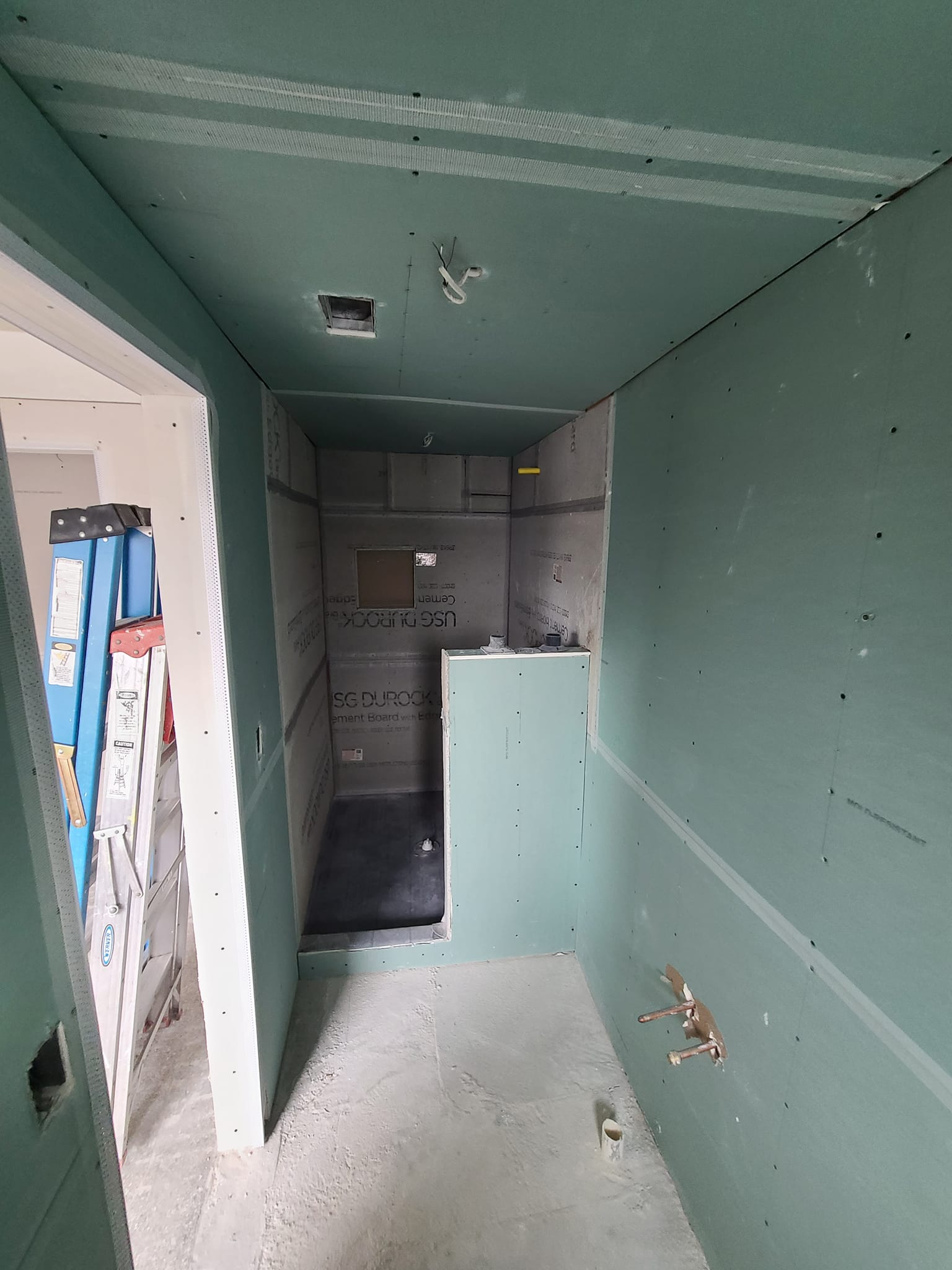 Bathroom under construction showing green cement board and shower framing