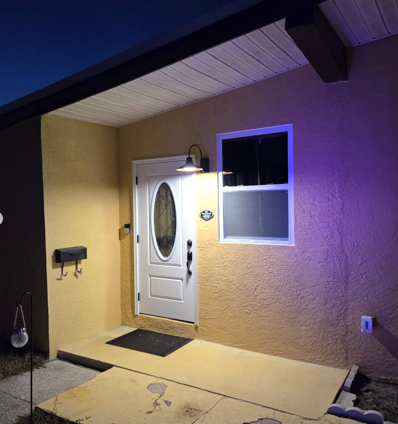 Home entrance with white door and professional lighting at night