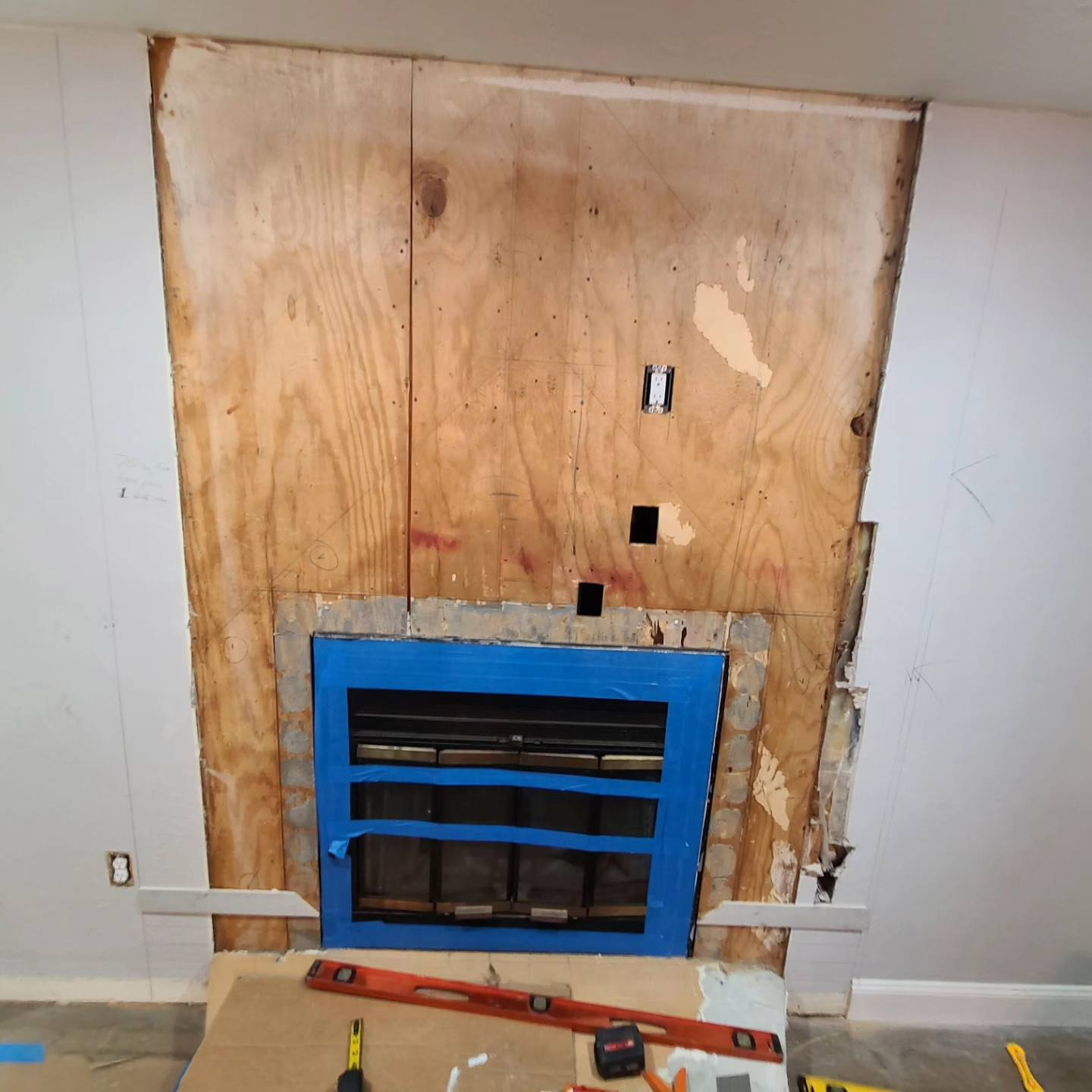 Fireplace under construction with exposed plywood backing