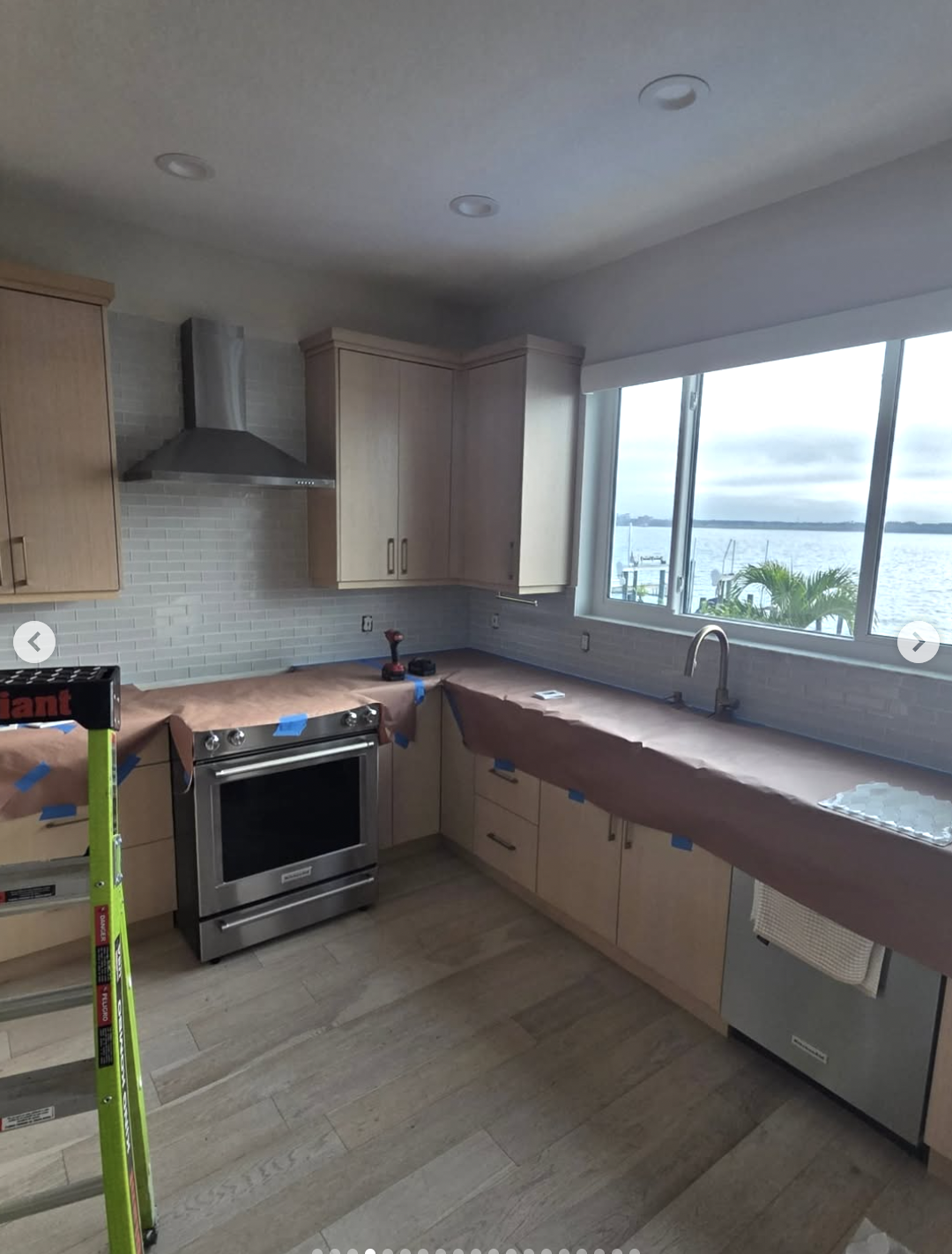 Kitchen renovation in progress with ocean view windows and light wood cabinets